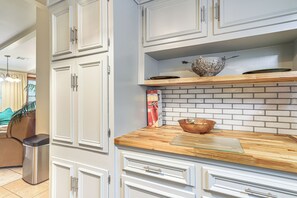 A kitchen with white cabinets, a wooden countertop, and a backsplash.