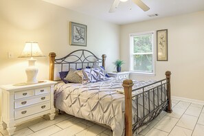 A bedroom with a bed, nightstand, lamp, dresser, and framed pictures on the wall.