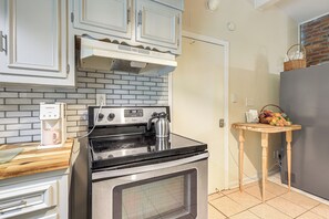 A kitchen with a stove, a coffee maker, and a small table with fruits. - Cozy Georgia Gem on 3.5 Acres: Eat, Shop, Explore! (Fayetteville)
