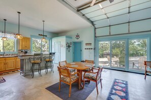 Een ruime keuken met houten kastjes, een eethoek met een ronde tafel en stoelen, en een grote schuifpui die uitkomt op een terras.