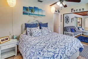 Un dormitorio con una cama grande, una mesita de noche, una lámpara de pared y un ventilador de techo.