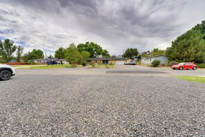 A residential area with houses, a gravel driveway, and parked cars.