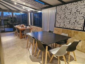 Un comedor moderno con una gran mesa y sillas, un muro con estampado y vistas amplias a través de grandes ventanales.