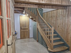 Un escalier en bois, doté d’une rampe, mène à une porte.