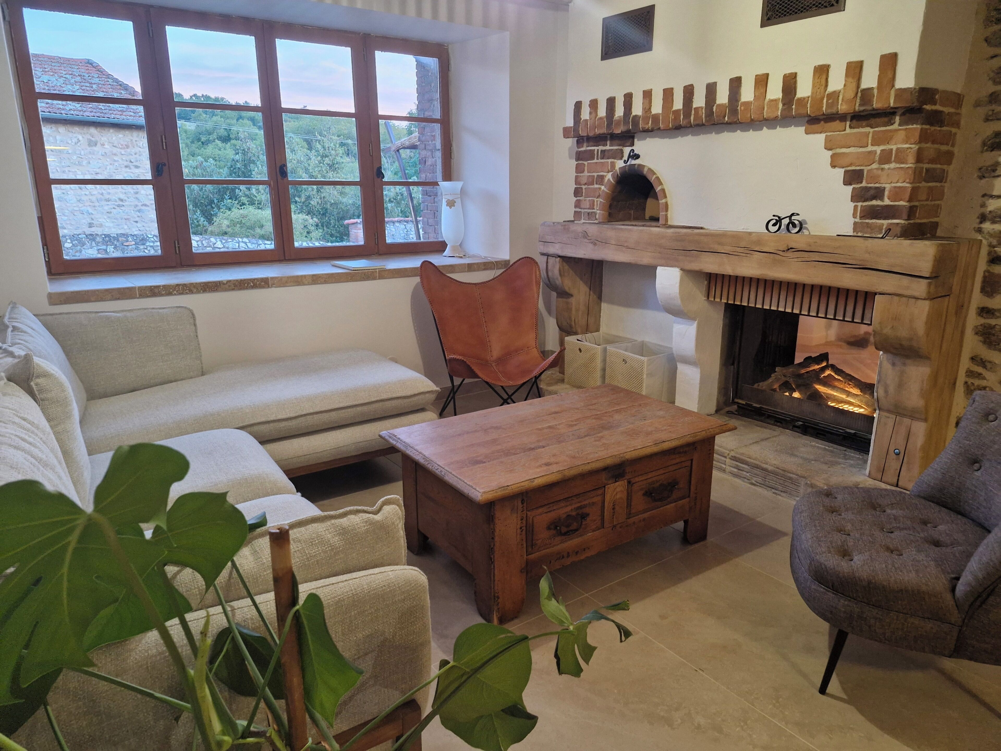 A cozy living room with a fireplace, a sofa, a wooden coffee table, and a chair.