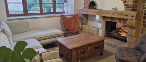 A cozy living room with a fireplace, a sofa, a wooden coffee table, and a chair.