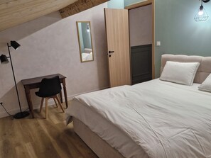 A bedroom with a bed, a desk, a chair, a mirror, and a wardrobe. - Grande maison avec piscine et vue sur le Pilat (Maclas)