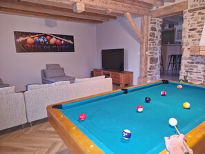 A pool table with balls, a television, and a sofa in a room with stone walls and wooden beams. - Grande maison avec piscine et vue sur le Pilat (Maclas)