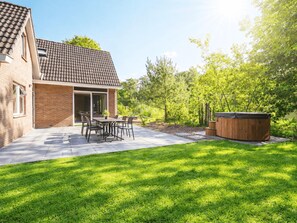 Ein Garten mit Terrasse, Whirlpool und Rasenfläche.