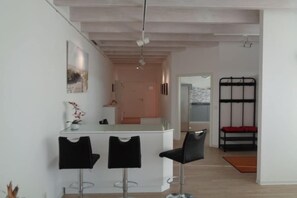 A modern interior with a kitchen area, a dining space with bar stools, and a bunk bed. - Holiday apartment with 2 bedrooms (Steinweiler)