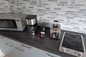 A kitchen with a microwave, coffee maker, toaster, and a portable induction cooktop. - Holiday apartment with 2 bedrooms (Steinweiler)