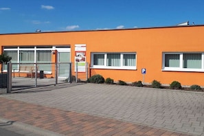 Een gebouw met een platte gevel, een parkeersign en een hekpoort.
