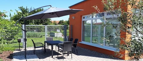 Un patio al aire libre con una mesa y sillas, una sombrilla y un edificio con ventanas amplias.