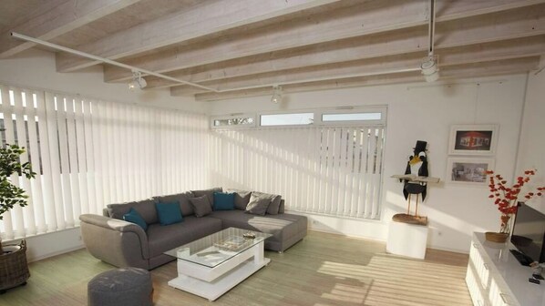 A modern living room with a sectional sofa, a glass coffee table, and a white console table with a TV. - Holiday apartment with 2 bedrooms (Steinweiler)