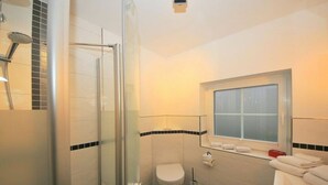 Ein Badezimmer mit Duschkabine, Toilette und Fenster.