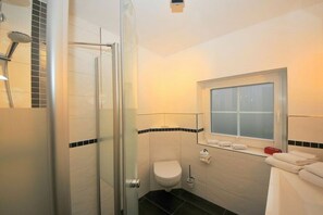 Un baño con cabina de ducha de vidrio, inodoro y ventana.
