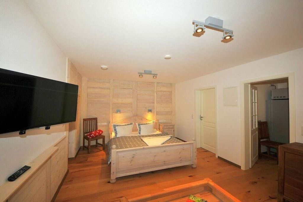 Un dormitorio con cama, televisión, silla y escritorio.