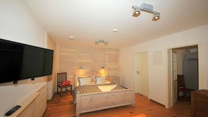 Ein Schlafzimmer mit Bett, Fernseher, Stuhl und Schreibtisch.