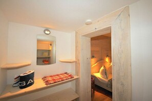 A bathroom with a wooden door, a mirror, and a shelf with towels and a roll of toilet paper. - Holiday apartment in Juist with swimming pool (Juist)