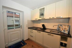 A compact kitchen with white cabinets, a black countertop, and a small sink. - Holiday apartment in Juist with swimming pool (Juist)