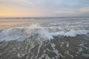 Uma praia com ondas se aproximando da costa.