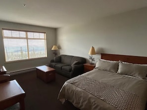 A hotel room with a bed, a sofa, a desk, and two lamps. - Cozy Studio with mountain views! (Beaverdell)