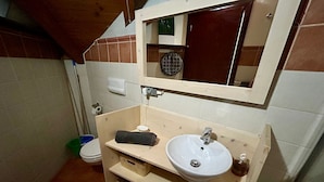 Une salle de bain avec un meuble-lavabo en bois, un lavabo blanc, un miroir et des toilettes.