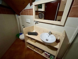 A bathroom with a wooden vanity, a white sink, a mirror, and a toilet. - Studio apartment in beachfront complex & 2 minutes walk to town (Santa Maria)