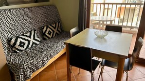 Une pièce avec un canapé à motifs, une petite table à manger et une vue par la fenêtre.