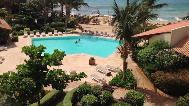 Un espace piscine avec des chaises longues et vue sur l’océan.