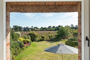 A view from a doorway to a garden with a lawn, a tent, and a house in the background. - Heidje-Hüs - "Heidje-Hüs" Hideaway (Kampen (Sylt))