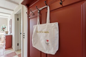 A beige tote bag hanging on a red door with a handle and hooks, and a white towel draped over the door. - Heidje-Hüs - "Heidje-Hüs" Hideaway (Kampen (Sylt))
