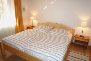 A single bed with a striped bedspread, two bedside tables with lamps, and a wooden floor. - Cozy vacation rental "Zur Hanse 1.2" with a terrace in the Baltic Sea spa town of Zingst - (Zingst)