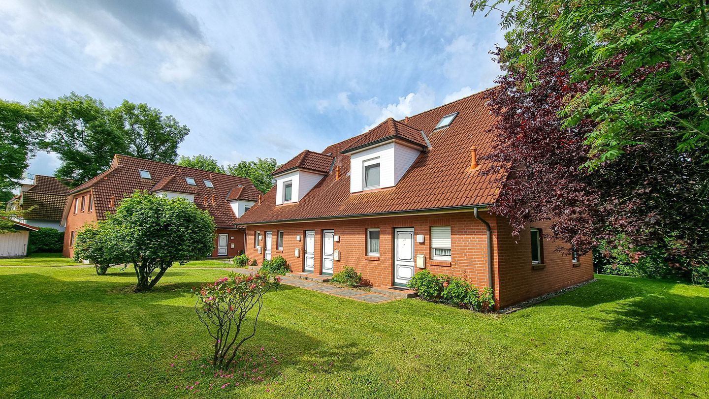 A two-story brick house with a sloped roof, a front porch, and a well-maintained lawn.