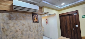 A reception area with a wooden textured wall, a framed religious figure, a fire extinguisher, and a door marked with the number 411.