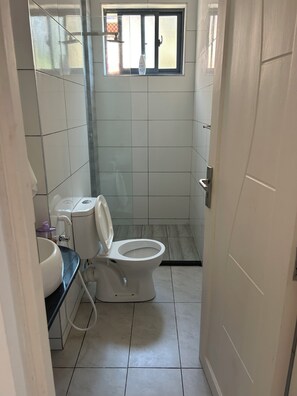 A small, tiled bathroom with a toilet, a sink, and a window. -
Cozy 1 bedroom with AC and hot shower. 3 mins to the beach. Pool, gym/game room (Mombasa)