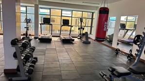 Une salle de sport équipée de tapis de course, d’appareils de musculation et d’un sac de frappe.