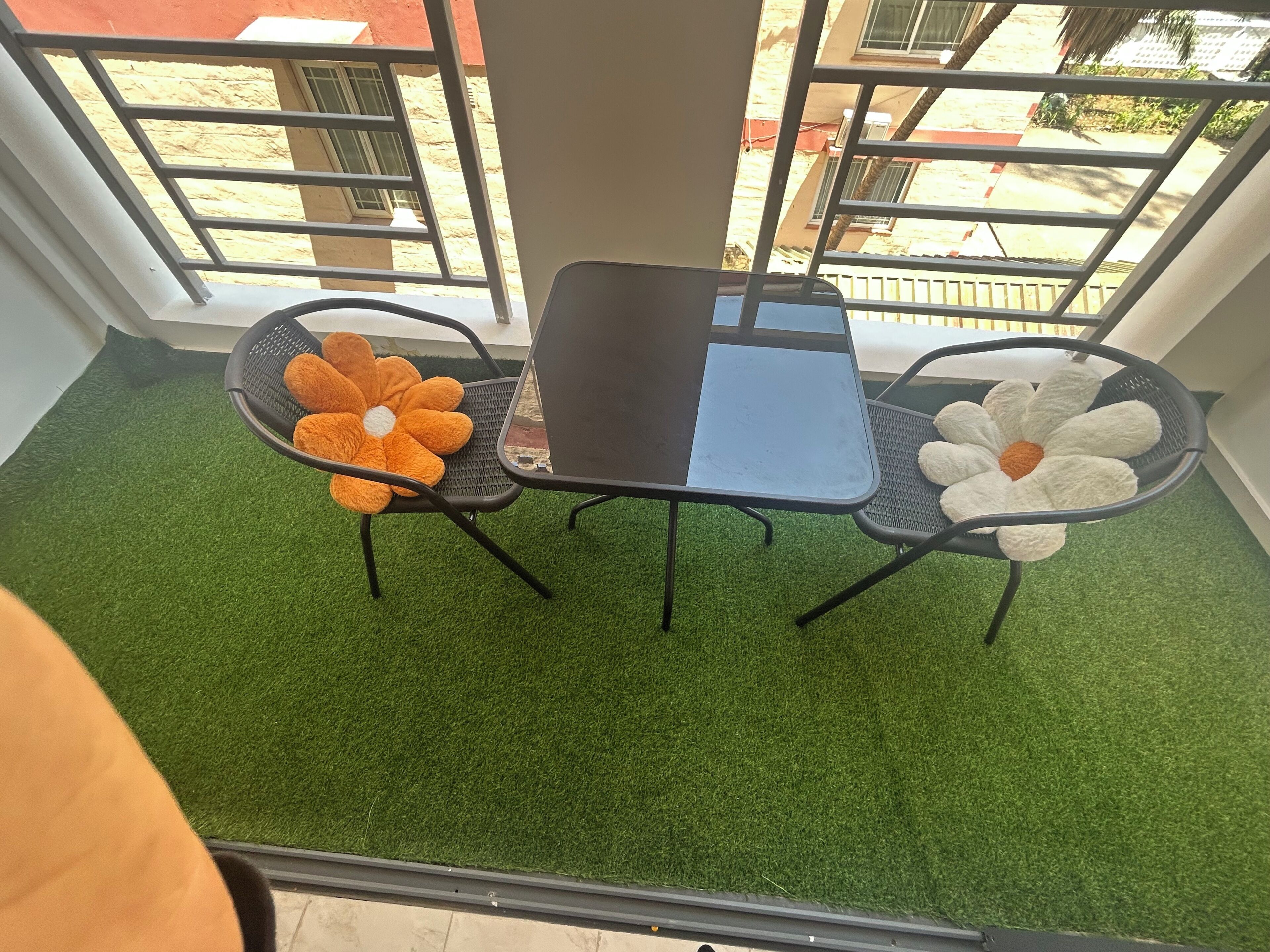 A balcony with a small table and two chairs, surrounded by artificial grass.