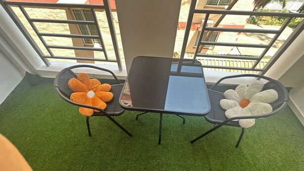 Un balcon avec une petite table et deux chaises, entouré de gazon synthétique.