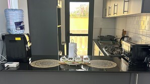 Une cuisine moderne dotée d’un îlot central, d’un distributeur d’eau et offrant une vue à travers une porte.