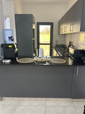 Une cuisine moderne dotée d’un îlot central, d’un distributeur d’eau et offrant une vue à travers une porte.