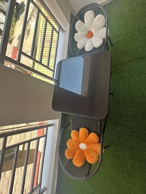 A room with a table and two chairs, one with a flower cushion and the other with a tablet. - 
Cozy 1 bedroom with AC and hot shower. 3 mins to the beach. Pool, gym/game room (Mombasa)