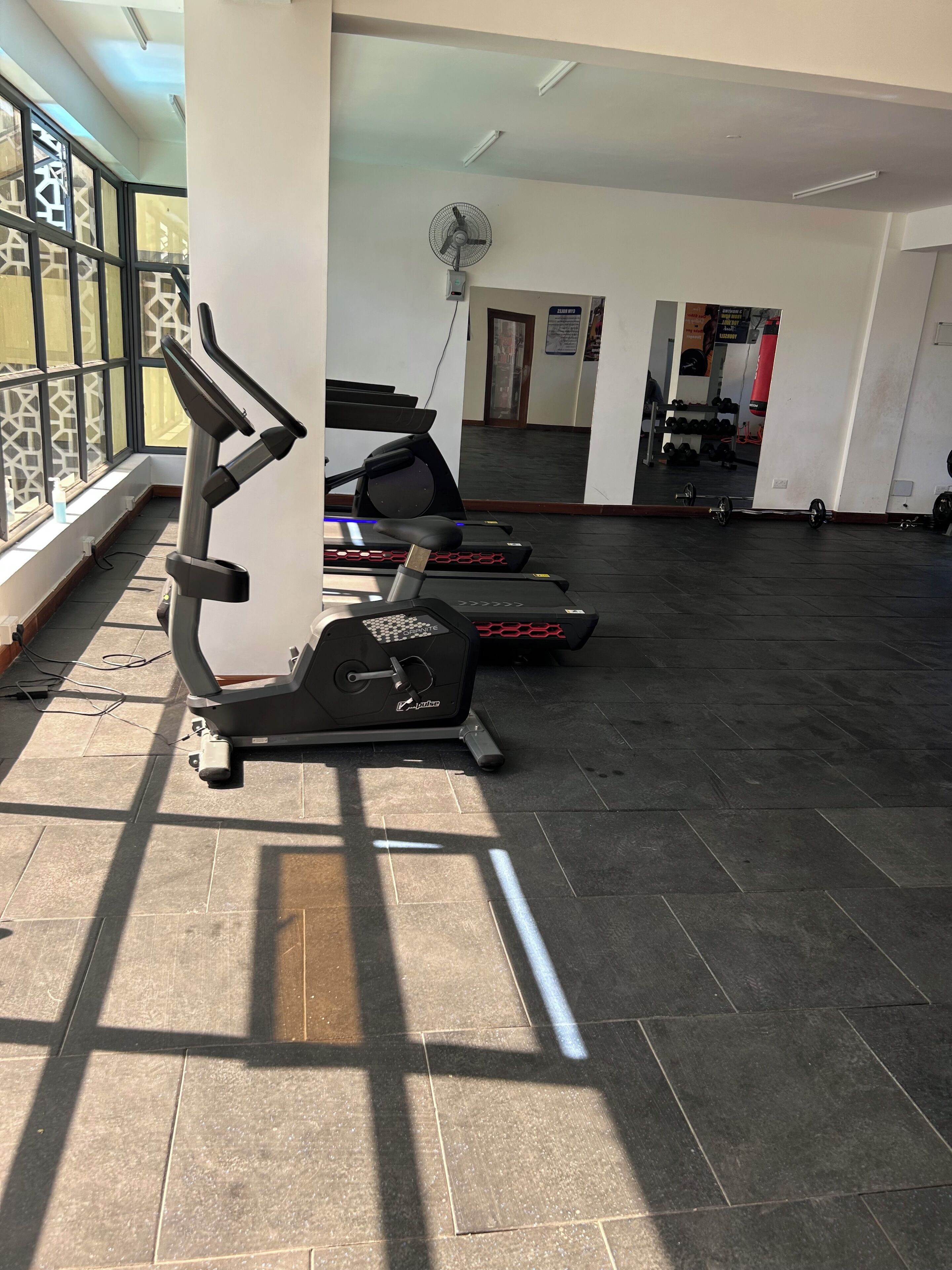 Ein Fitnessraum mit Trainingsgeräten, einem großen Spiegel und einem Fenster mit Blick.