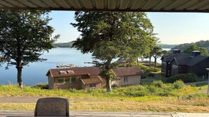 En fastighet vid sjön med en inglasad veranda, trähus och utsikt över vattnet.