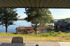 A lakeside property with a covered deck, wooden buildings, and a view of the water. - 4 star holiday home in UDDEVALLA (UDDEVALLA)