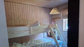 A bunk bed room with a ladder, wooden walls, and a hanging light fixture. - 4 star holiday home in Sæby (Sæby)
