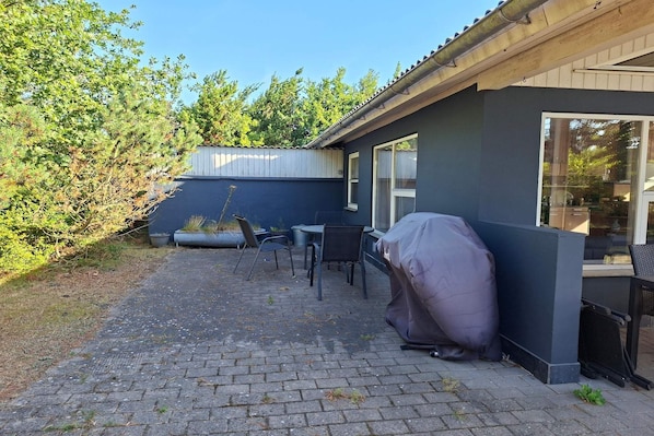 A patio with a barbecue grill, outdoor seating, and a view of the surrounding area. - 4 star holiday home in Sæby (Sæby)