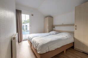 A bedroom with a double bed, a wooden wardrobe, and a sliding glass door leading to an outdoor area. - Nature Escape With Private Patio (Ruinen)