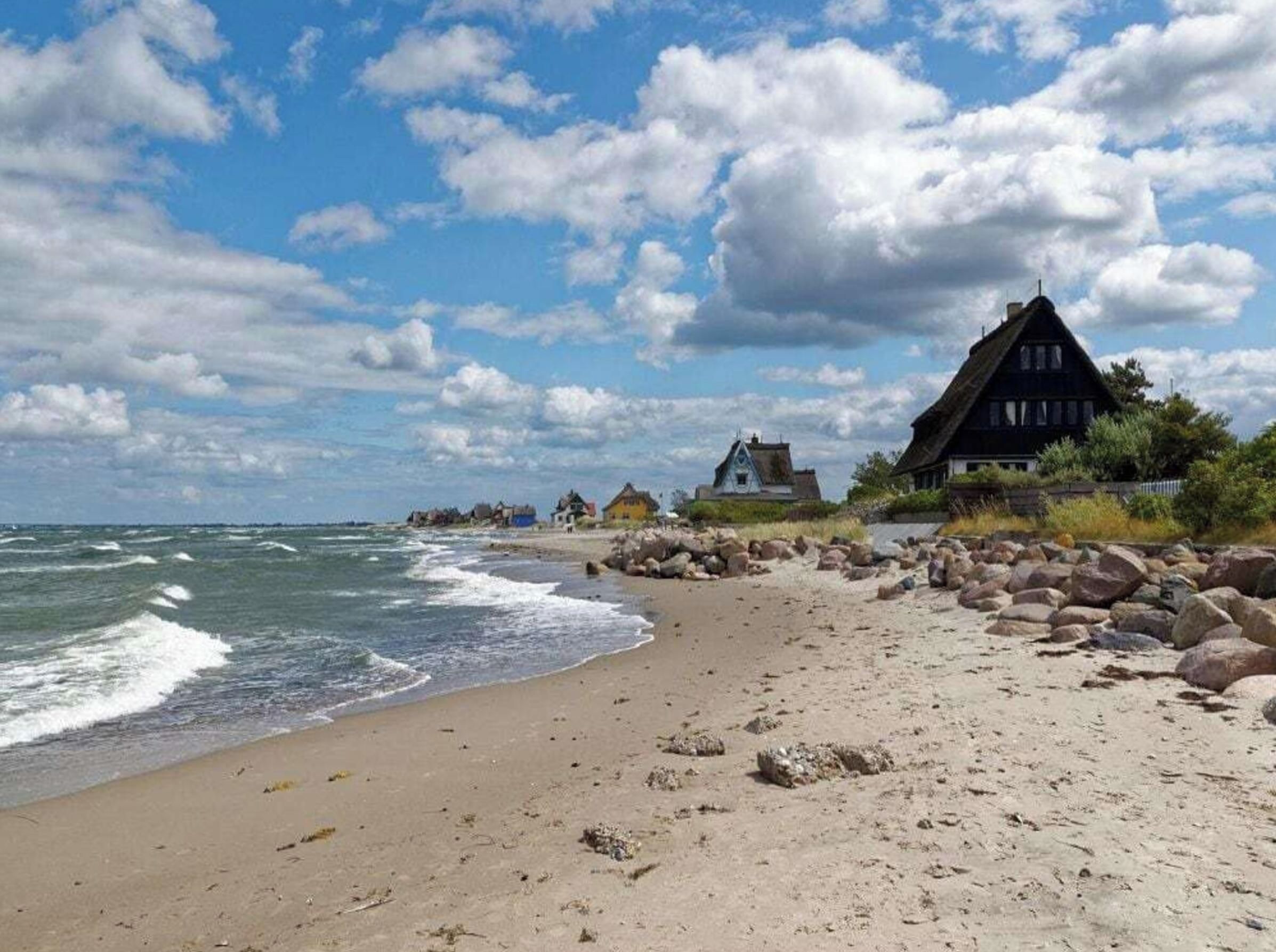 Ein Strand mit einem Haus und felsigem Ufer.
