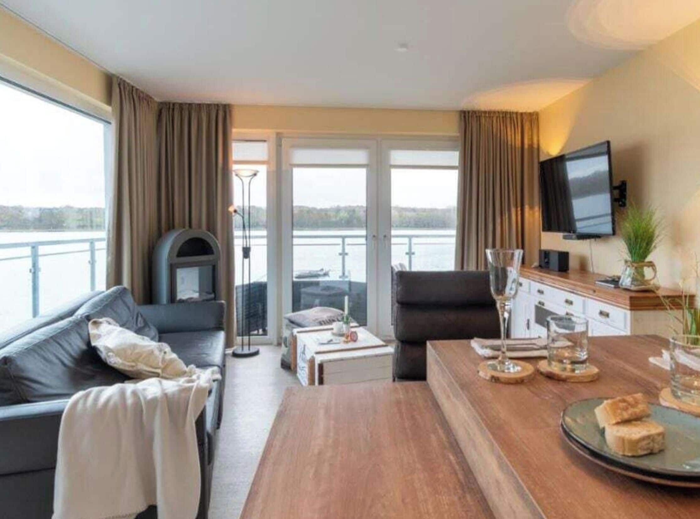 Ein modernes Hotelzimmer mit einer Couch, einem Couchtisch, einem Fernseher und Blick auf das Wasser.